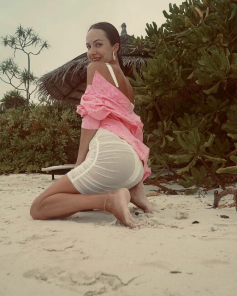 Супруга Остапчука сексуально присела на пляже в полупрозрачном платье (фото)
